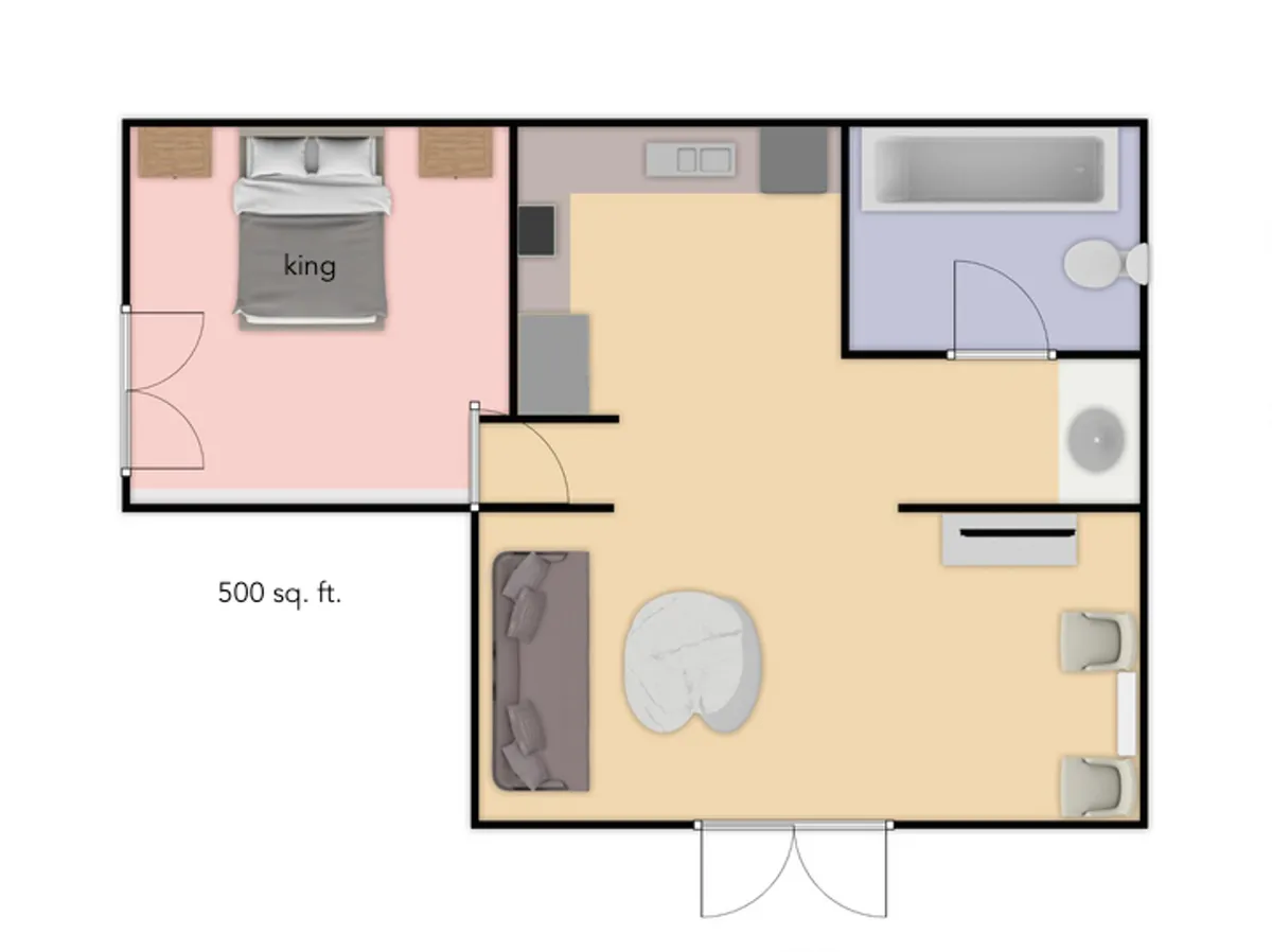A cozy open-plan living area that includes a king bed, a premium sleeper sofa, and a bathtub visible in the background. The room is warm and inviting, with a soft color palette, functional furnishings, and an overall sense of comfort and flexibility for families or groups.